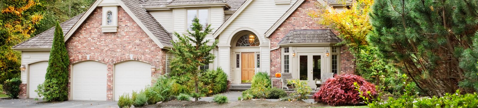 Large suburban house with double garage doors surrounded by lush landscaping in Saratoga Springs