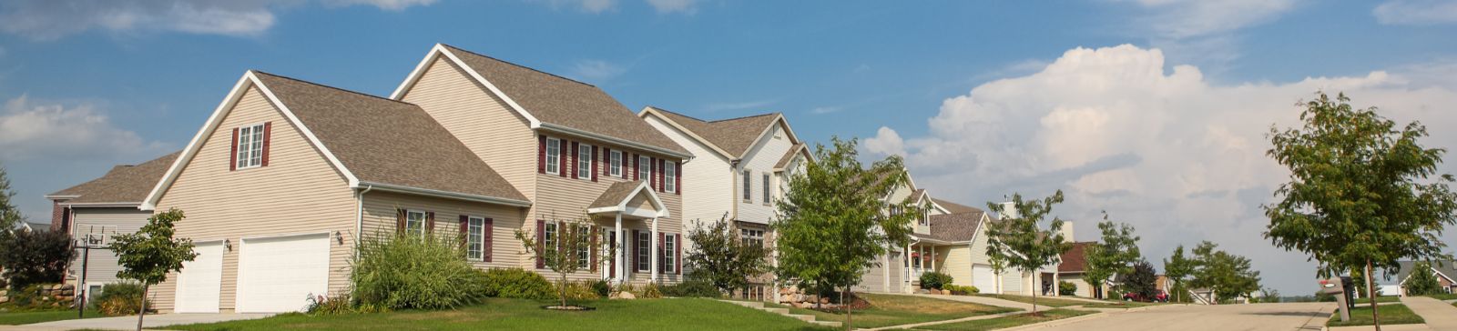 Row of suburban homes with double garage doors under a blue sky in Saratoga Springs, Utah
